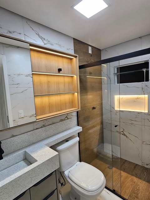 Banheiro planejado com espelho, nichos iluminados e box de vidro