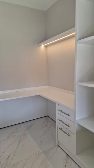 Home office branco em L com gaveteiro, nichos e iluminação